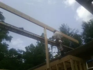 Carpenter setting a ridge beam over a new addition frame — Ice Dam Removal by Roofing Brothers in Imlay