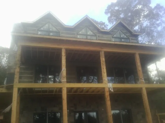 Dormers and porch framing on a large log home under construction — Roof Coating work by our crew in Imlay