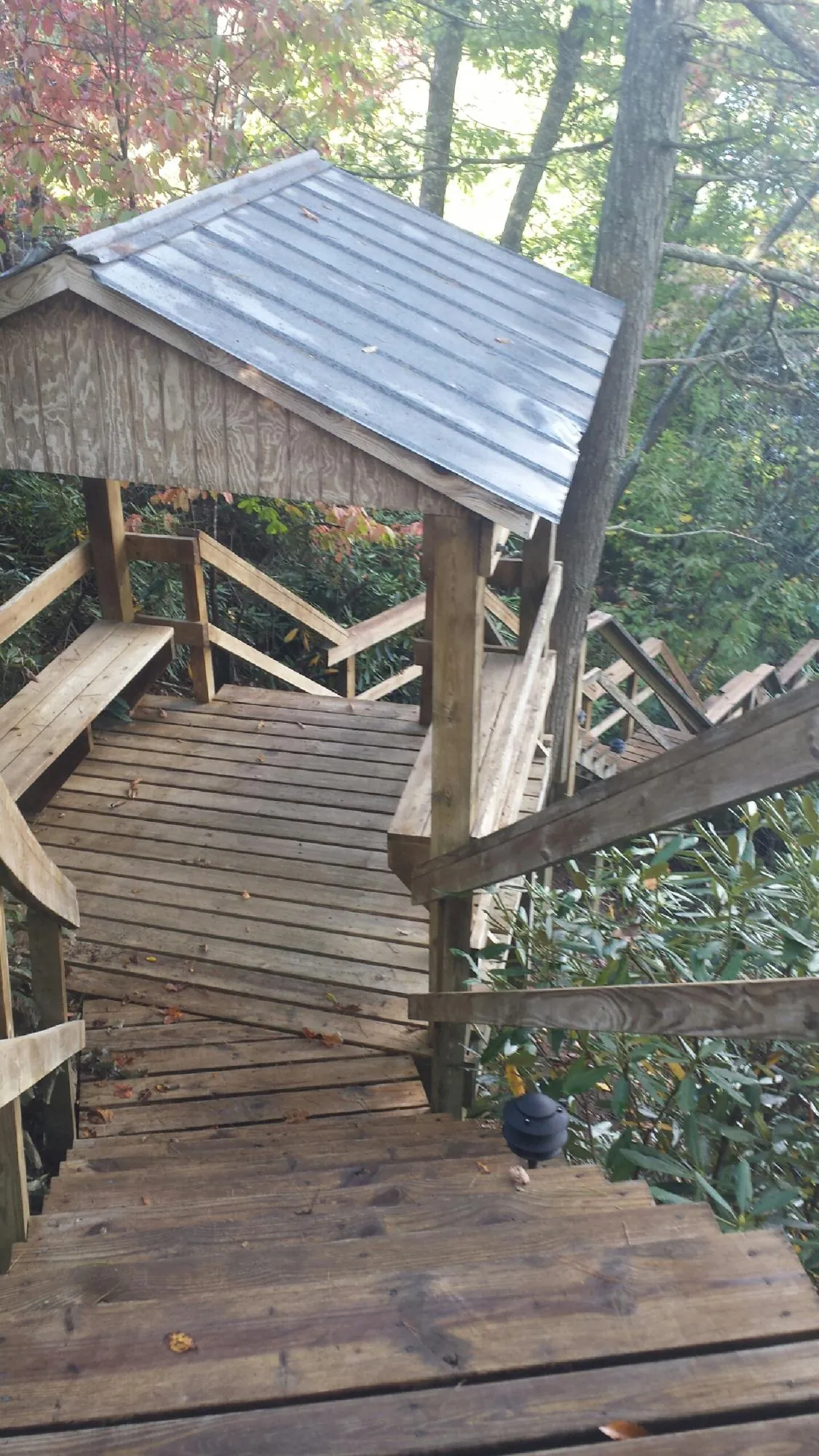 Metal roofed shelter over wooden steps on a wooded walkway — Skylight Repair & Installation work by our crew in Imlay